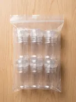 Six empty transparent 50 ml chili mills in a plastic bag